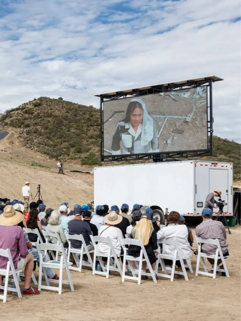 Large outdoor audience watching performative art on a mobile LED screen during the Aspen AIR Festival art installation.